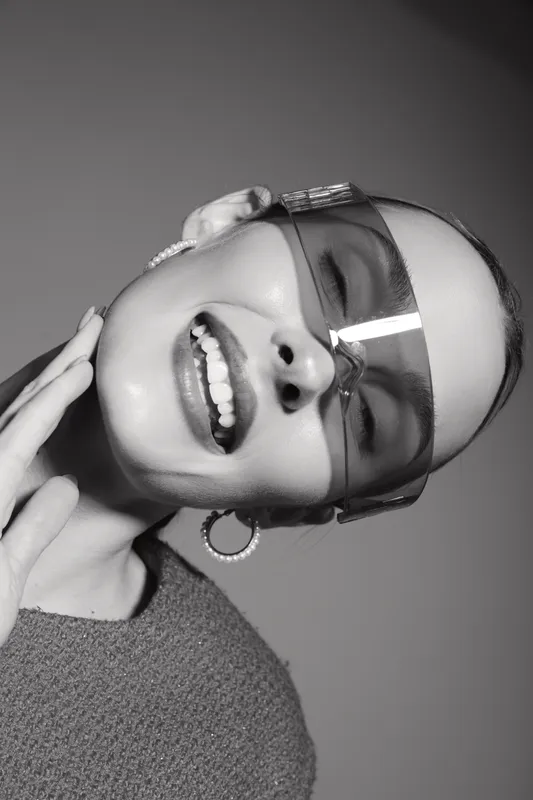 Close up of smiling Asian woman with light skin wearing sunglasses and earrings in studio. Concept of fashion, beauty, and modern style.