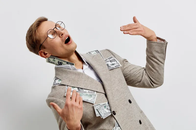 surprised caucasian man wearing eyeglasses creative business suit with dollar bills caught in jacket pockets posing excited isolated on plain white background digital nomad concept
