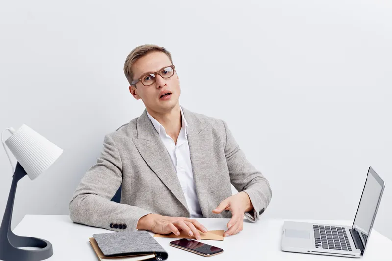young man working digital nomad gray blazer glasses use laptop smartphone modern office white background