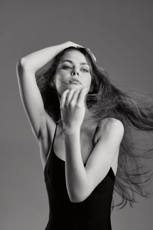 Black and white portrait of young woman with flowing hair and relaxed expression in minimalistic style.