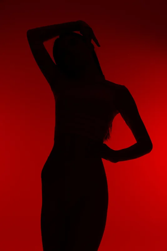 Silhouette of a woman sport fitness in dynamic pose against bright red background, highlighting active lifestyle and strength in minimalist composition.