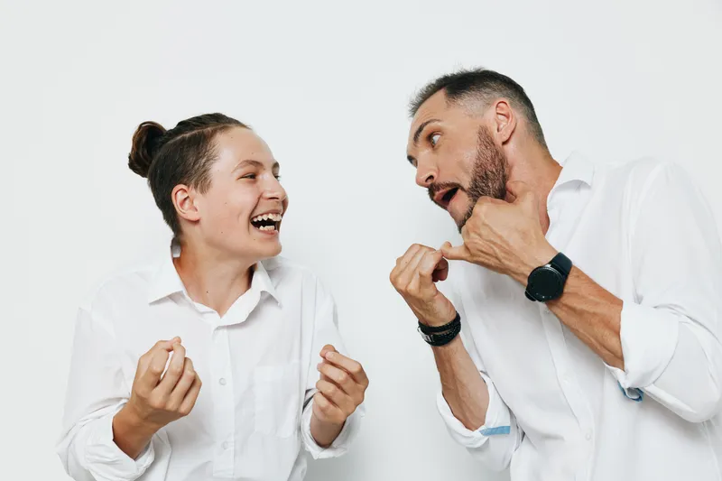 A business professional man and colleague share a lively moment against a solid color background, showcasing confident energy, teamwork, and genuine emotion in a polished professional setting.