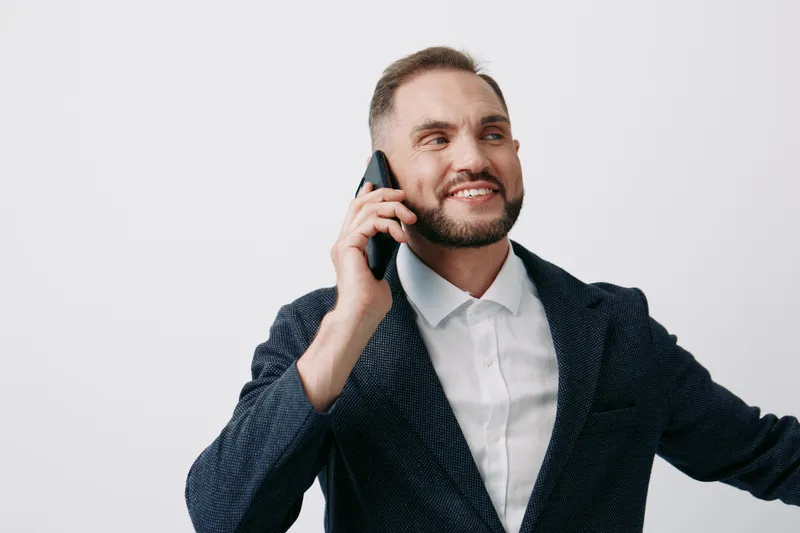 Professional businessman on a mobile call, confident and upbeat, wearing a blazer. Isolated color background highlights his focused presence and professional mood during a workday moment.