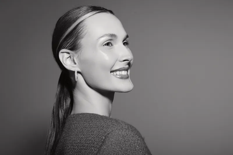 Smiling Caucasian woman with light skin and dark hair in profile on grey background. Concept of happiness, beauty, and natural expression.