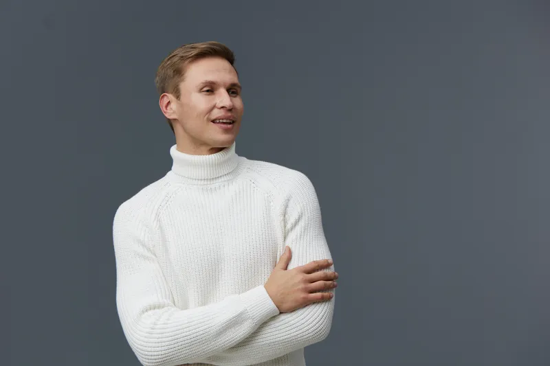 Smiling young caucasian man wear white turtleneck sweater stand crossed arms look aside isolated on gray background cheerful casual style studio portrait digital nomad work concept