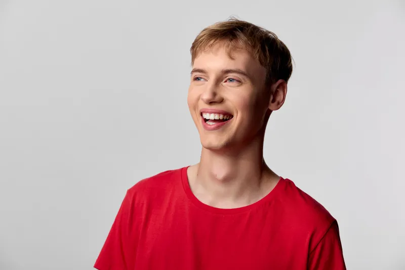 Smiling man in a red shirt with a casual look, cheerful mood, studio lighting, clean simple background, headshot style for lifestyle fashion or marketing use