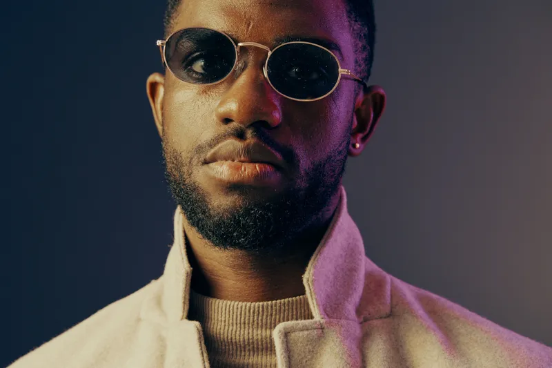 Stylish African man with sunglasses exuding confidence against a colorful background showcasing a modern fashion vibe