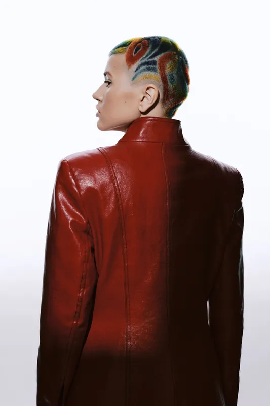 woman with colorful shaved hairstyle wearing red leather jacket, side profile, modern fashion, ethnic features, urban style, creative expression
