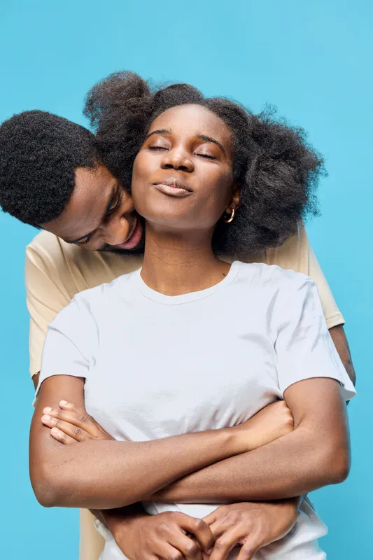 Happy couple embracing with joy against a bright turquoise background, showcasing love, connection, and celebration of diversity in intimate moments