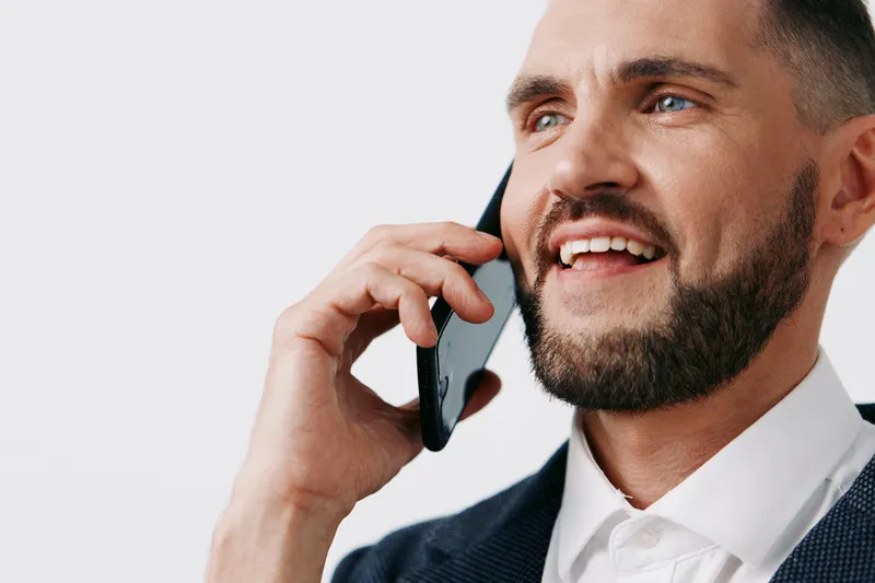 Professional businessman on a colored isolated background talks on a mobile phone with a confident, upbeat expression, signaling leadership and strong communication in a modern corporate setting.