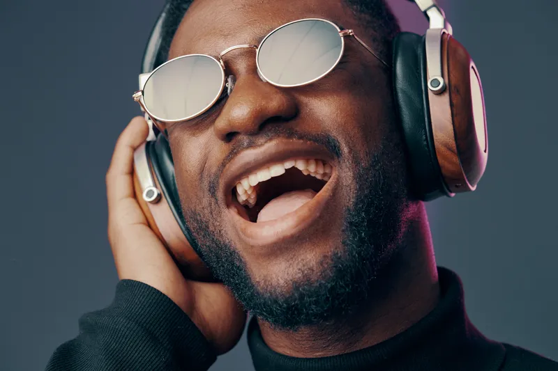 Happy Black man enjoying music with headphones, expressing joy and energy in a vibrant, modern setting Perfect for music and lifestyle themes