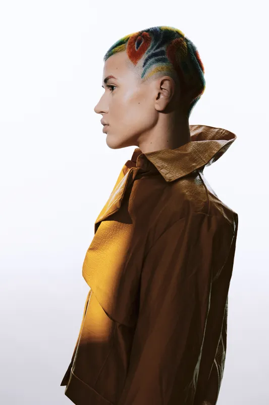 profile of a woman with colorful short hair wearing a brown jacket, modern fashion style, light background, artistic portrait, urban look, vibrant hairstyle