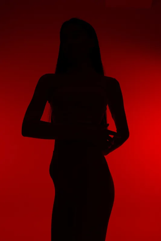 Silhouette of a woman sport fitness figure against a vibrant red background, emphasizing active lifestyle and body shape in dramatic lighting.