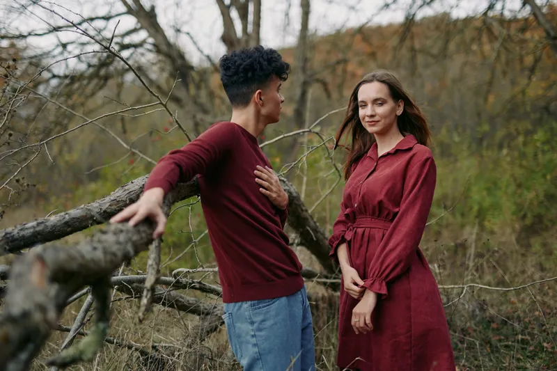 Candid portrait of a young couple in a natural woodland setting, genuine interaction and subtle emotion captured with authentic, believable expressions and relaxed body language.