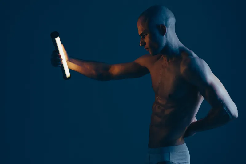 Strong man holding a flashlight, showcasing determination in a dark environment. The dim lighting adds a dramatic touch, creating an engaging atmosphere.