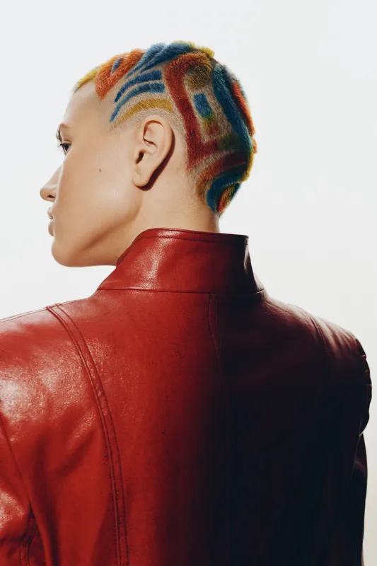 Woman with colorful shaved hair and red leather jacket, trendy hairstyle, side profile, artistic expression, modern fashion, bold look
