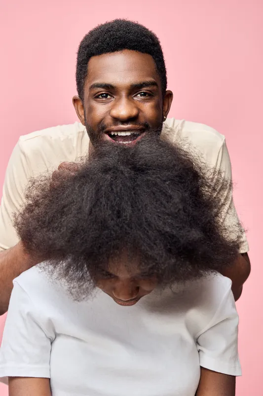 Happy young couple with natural hair against a pink background, showcasing hairstyles and joyful emotions, perfect for hair care concepts and diversity representation