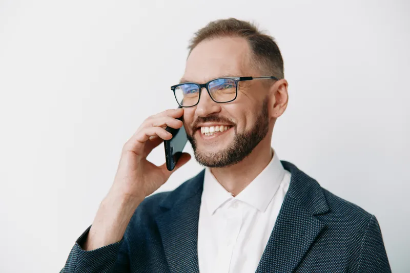 A professional businessman on a call, smiling confidently. The isolated colored background emphasizes focus on success, strategy, and positive emotion in a corporate setting.