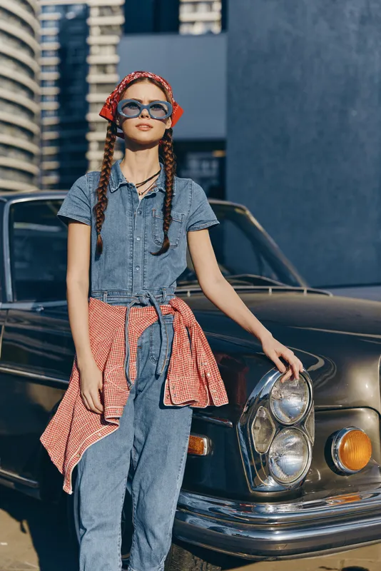 modern boho-western denim street style woman wearing sunglasses with braided hair and a red bandana in film color outdoors