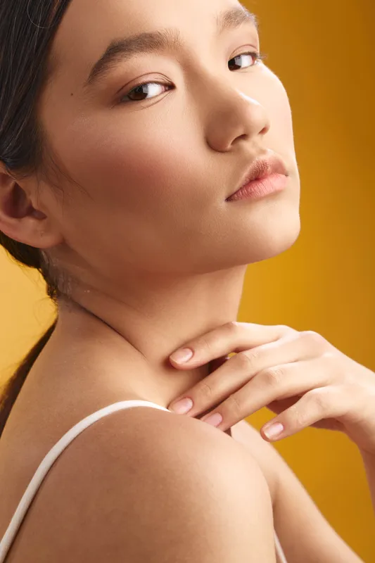 Asian woman is featured in a close portrait with graceful expression, soft lighting, and smooth skin, creating an elegant and intimate mood that conveys calm confidence and refined beauty.