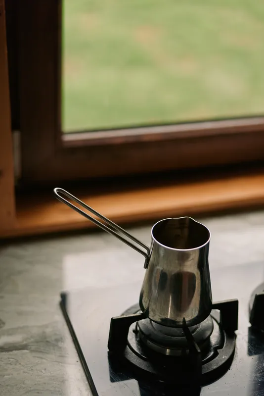 Kettle on a gas stovetop beside a metal burner in a kitchen scene, showcasing cookware simplicity and a warm, everyday home cooking atmosphere