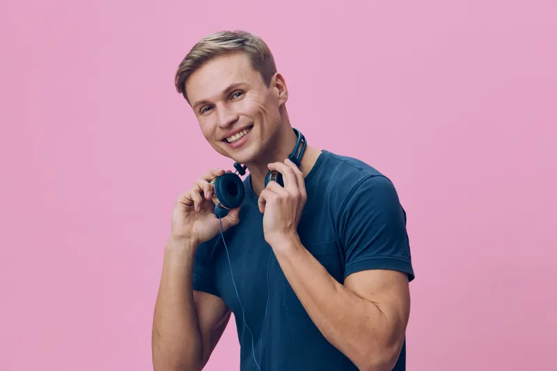 smiling young caucasian man casual t-shirt hold headphones prepare listen music isolated pink background technology lifestyle digital detox concept