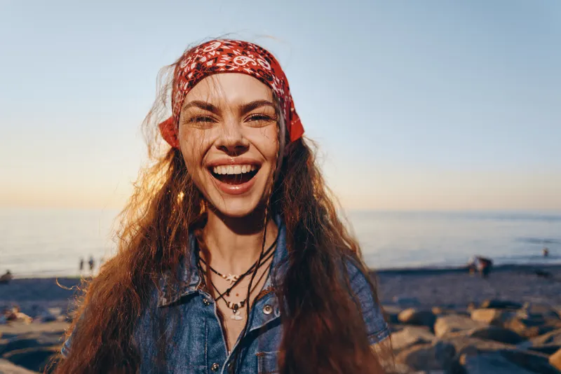 lifestyle woman in modern boho-western denim street style laughing joyfully at sunset captured with warm film color tones