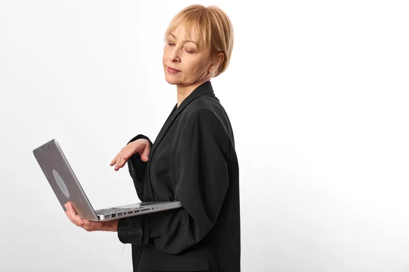 Stressed woman with laptop in black scrubs shows burnout fatigue and anxiety in healthcare, doctor overwhelmed in technology at white studio today alone