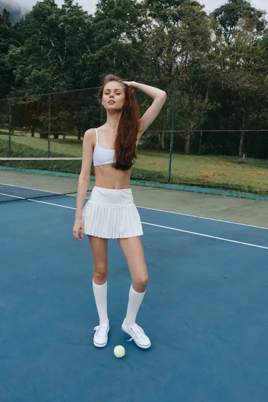 Young woman in sporty outfit on tennis court, showcasing confidence and athleticism in outdoor setting, perfect for health and fitness concepts