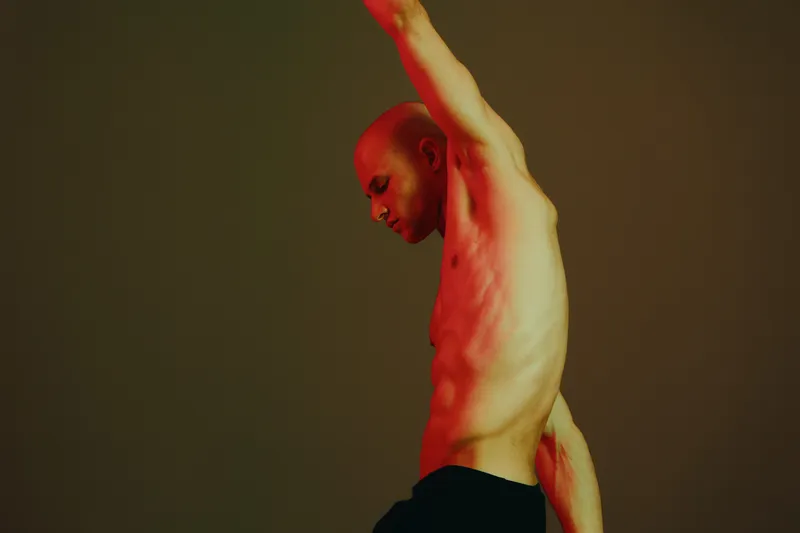 Athletic man posing under dramatic lighting, showcasing strength and determination with an energetic and stylized expression.