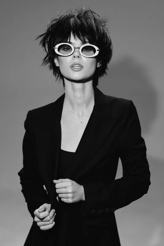Black and white portrait of stylish woman wearing sunglasses and a blazer with confident expression
