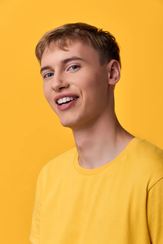Smiling man in a yellow shirt against a bright yellow backdrop, casual lifestyle image with cheerful expression and simple fashion, ideal for upbeat branding and social media