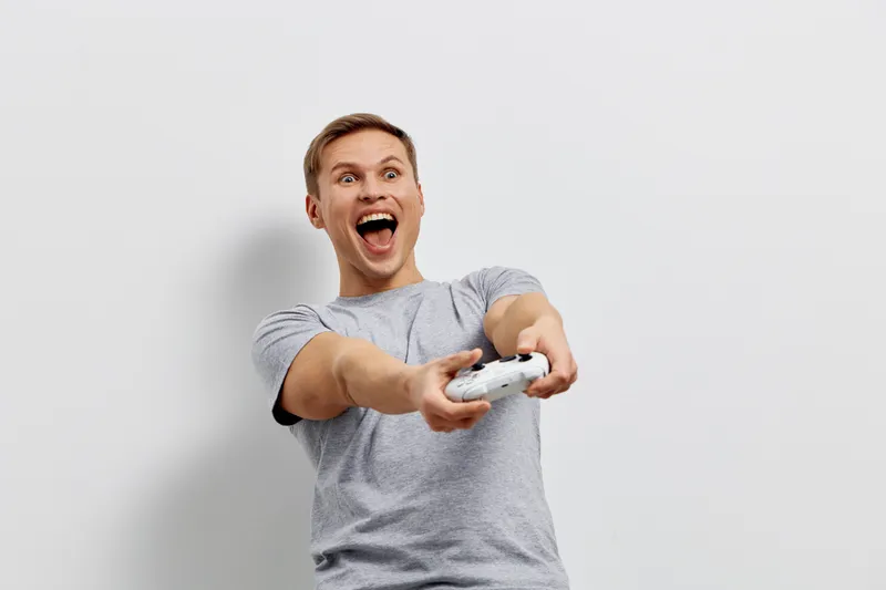 excited young caucasian man playing video game holding wireless controller isolated on white background digital entertainment concept