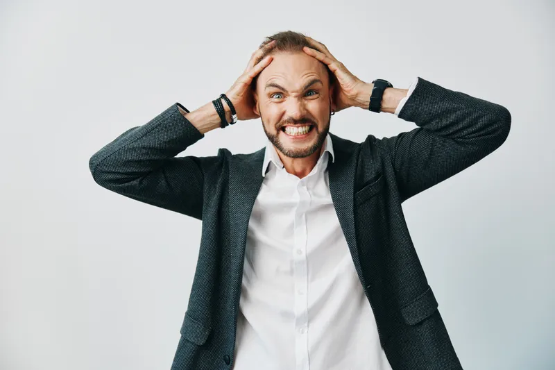 A professional man in a business outfit shows frustration against an isolated colored background, conveying urgency and determination through bold expression and tense posture.