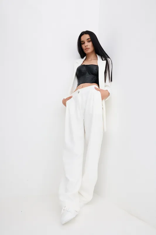 fashion woman wearing white pants and blazer with black top standing against white background, stylish pose, modern outfit details, clean minimalistic look