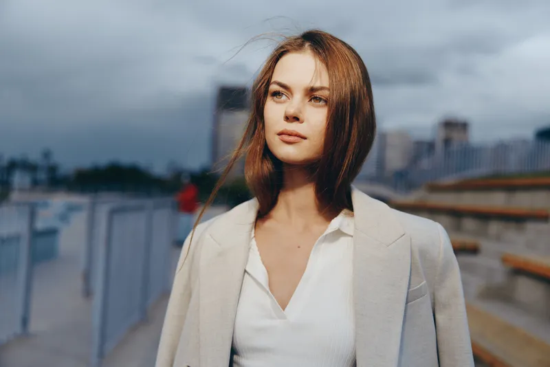 Confident businesswoman in a tailored coat, exuding poise and determination against a contemporary urban backdrop, embodying professionalism and style.