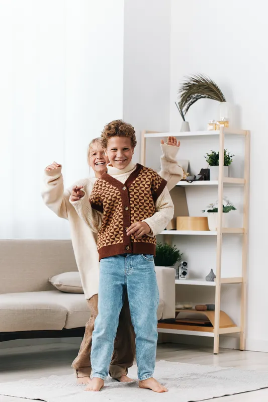 Two joyful figures dance together in a bright living room, showcasing warmth, energy, and playful mood amid cozy furniture and soft natural light.