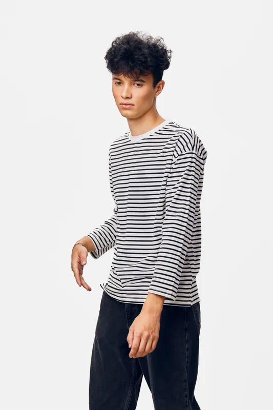 young man in striped shirt with curly hair posing against white background, casual style, contemplative expression, studio portrait in soft lighting