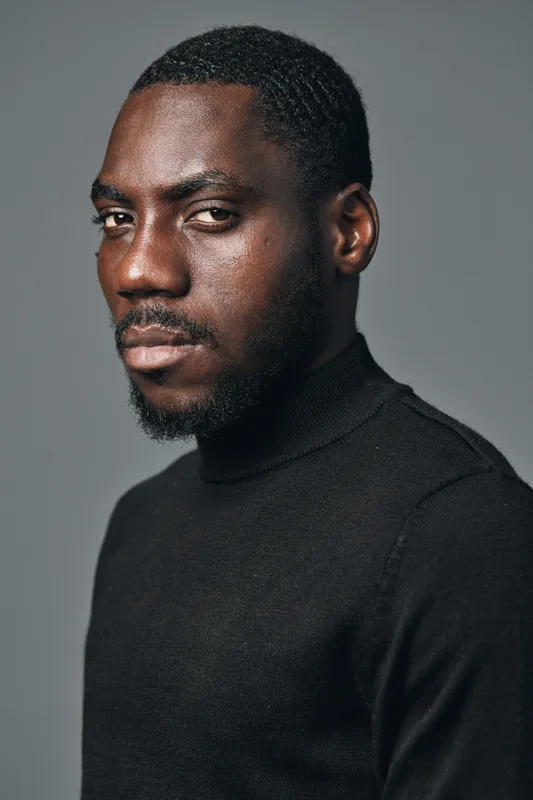 African man portrait with serious expression in creative conceptual visual style wearing black turtleneck on gray background. Closeup, confident and thoughtful male model with dark skin tone.