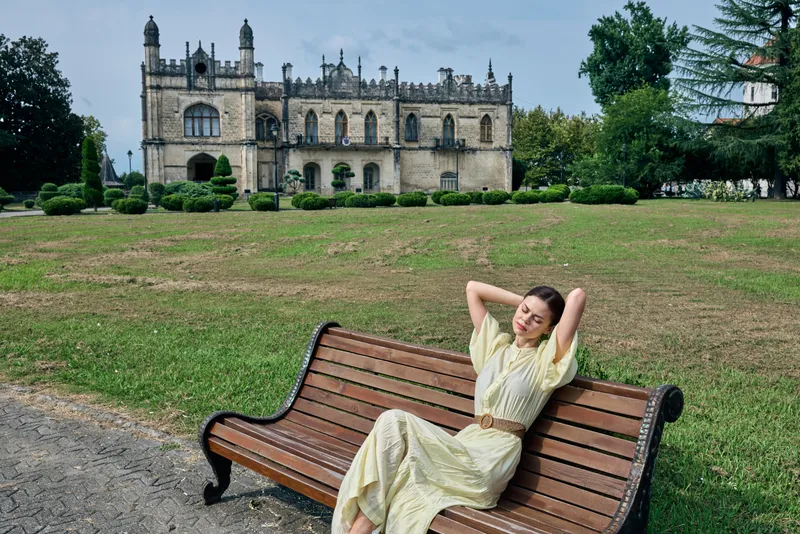 Woman on bench in park before mansion relaxing authenticity inclusivity