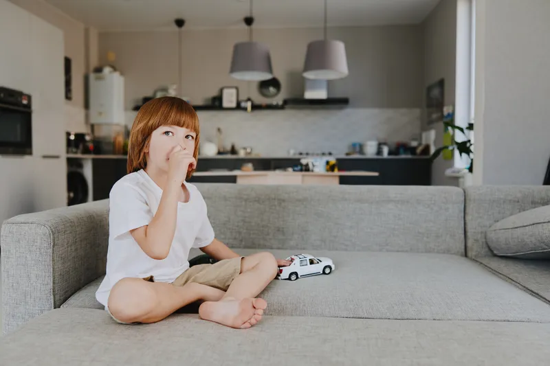 Young boy playing with a toy car in a cozy living room, showcasing a relaxed and playful atmosphere with soft colors and natural lighting.