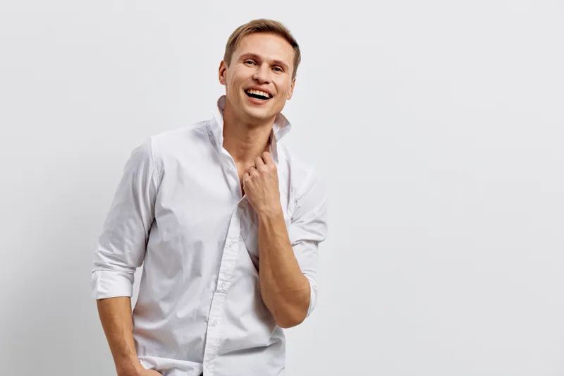 Cheerful smiling man wearing white shirt with rolled-up sleeves looking happy on plain gray background. People lifestyle concept, positive emotion, casual style, middle-aged male, joyful mood, studio 