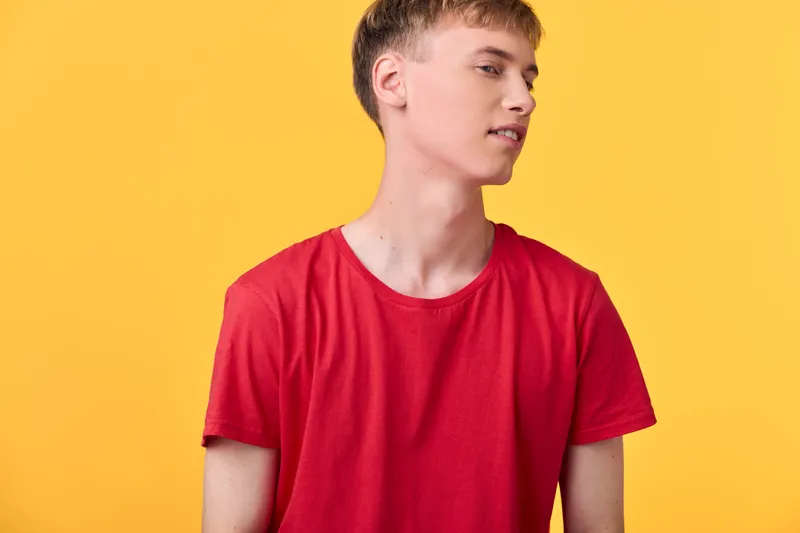 Young man, red shirt, casual, studio, yellow background, fashion, relaxed pose, bright color, clean composition, modern vibe, minimal setting, everyday style, confident look.