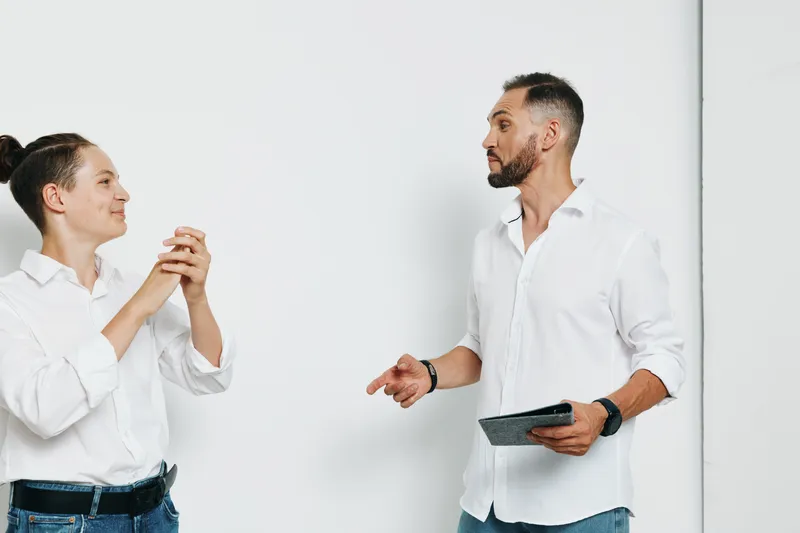 A professional business scene showing two men in white shirts against an isolated colored background, highlighting collaboration, confidence, and a positive, engaging dialogue.