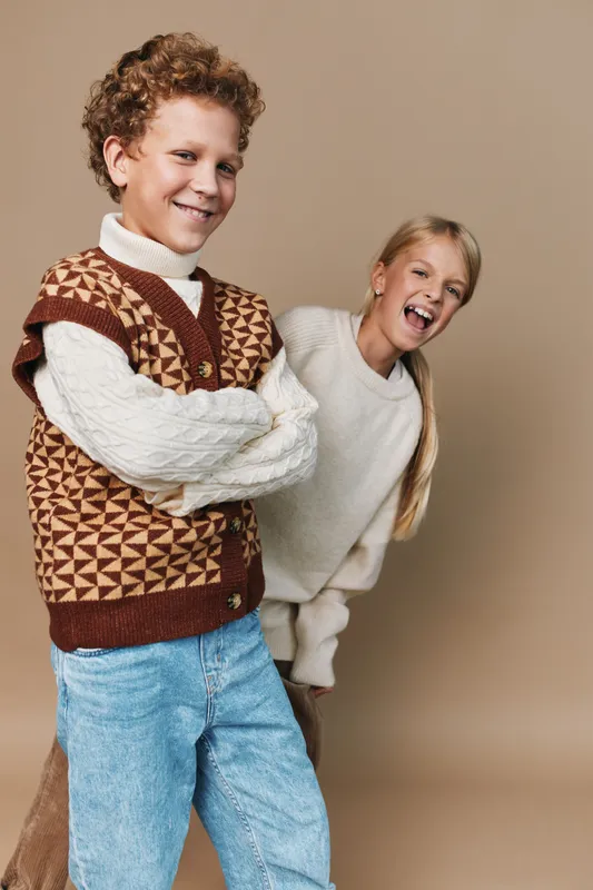 Authentic scene of playful children in cozy knitwear, highlighting school life and lifestyle moments during spontaneous play and warm friendship.