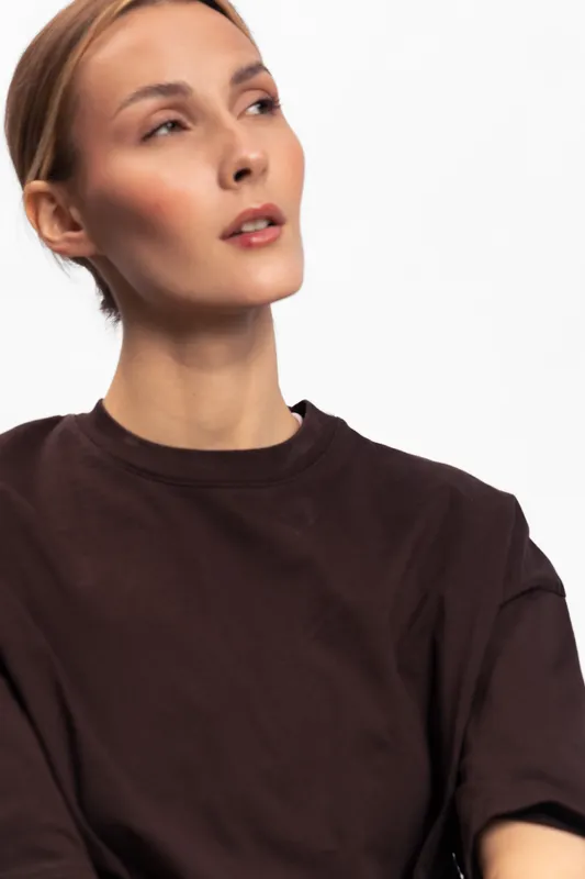 Portrait of a young woman with closed eyes wearing a dark brown t shirt isolated on white background. Concept for fashion, beauty, minimalism, and casual style.