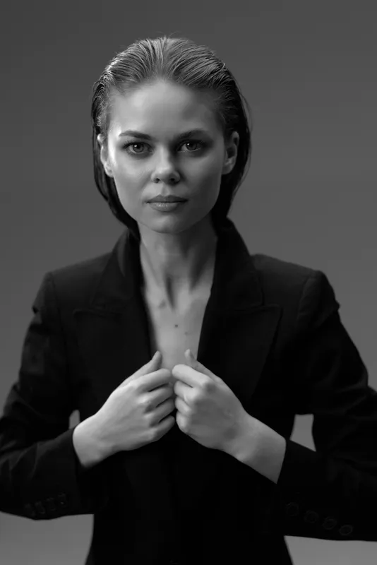 Black and white portrait of a serious woman in a suit with slicked-back hair and confident expression
