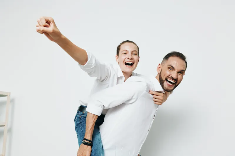 Confident business professional shares a joyful moment with a colleague against a solid colored background, presenting a professional demeanor with lively emotion, energy, and a dynamic, optimistic