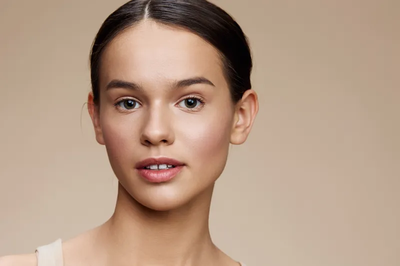 Natural beauty portrait of a young woman with light skin, soft makeup, and a neutral background conveying a sense of calm and freshness