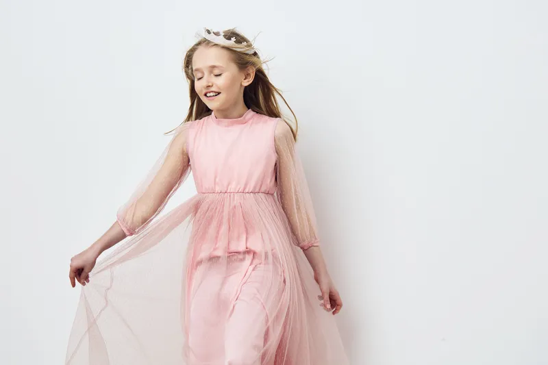 Charming young girl in a soft pink dress with flowing tulle, exuding joy and innocence, perfect for seasonal portraits or children s fashion photography